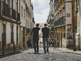 Give yourself enough time to get used to a new environment. Two people walking along a cobblestone street with bags.