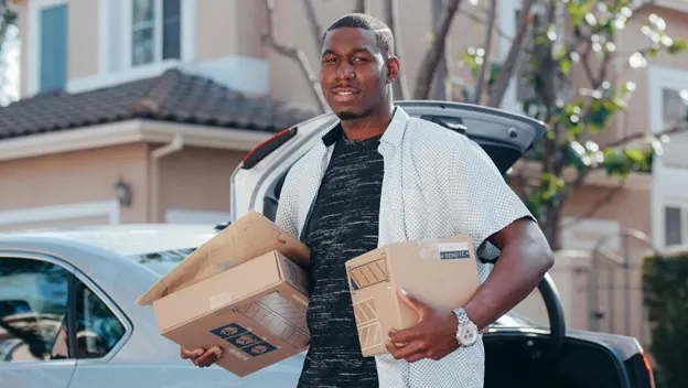 Person holding boxes in front of their car Person holding boxes in front of their car