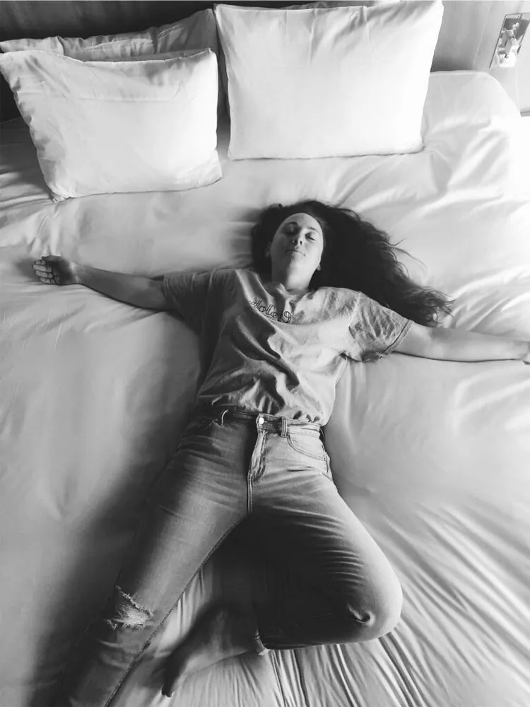 Make your bed early! A woman lying on top of a bed