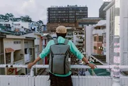 Give yourself enough time to observe your surroundings before doing anything. Person wearing a backpack overlooking a crowded urban area.