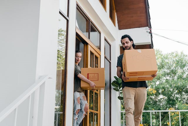 Couple carrying boxes from a house
