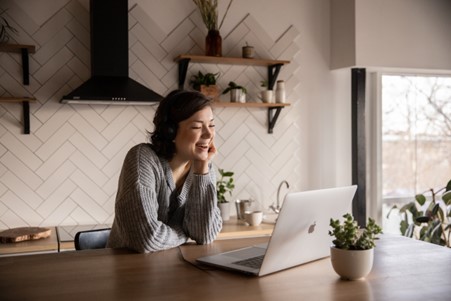 a smiling woman making a video call using a laptop