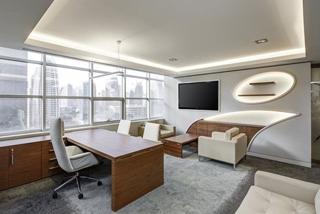 a home office with a desk, chairs, and a TV.